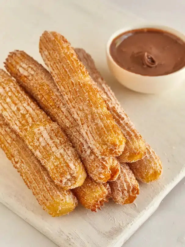 Churros croustillants saupoudrés de sucre servis avec de la pâte à tartiner Nucellina
